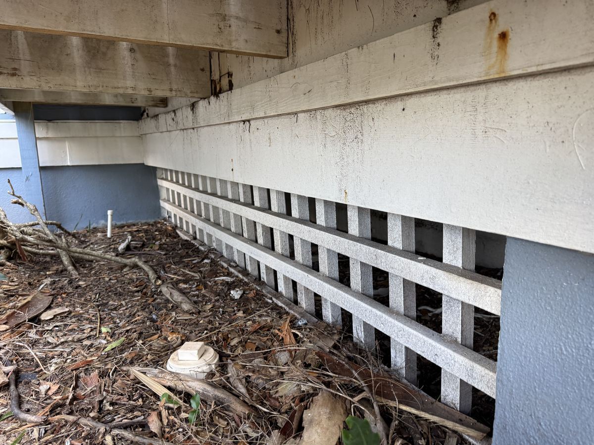 A long run of lattice skirting under a raised home, with gaps between the slats open to the crawlspace.