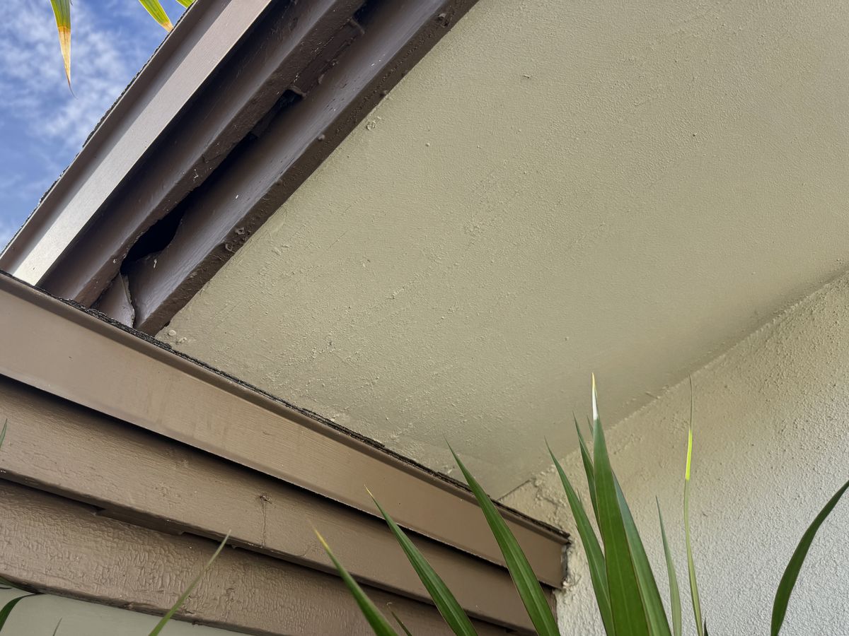 A stepped fascia corner where two roof lines meet, with a dark gap at the corner just above the lower roof edge.